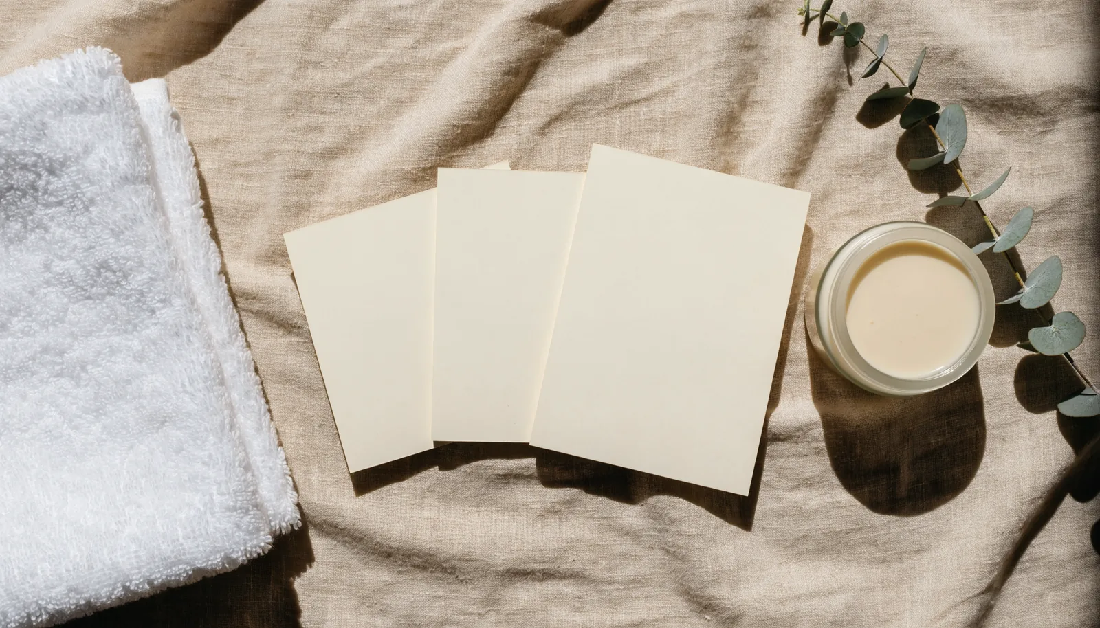 Three blank membership cards fanned beside a folded towel and a small skincare jar on a spa reception desk